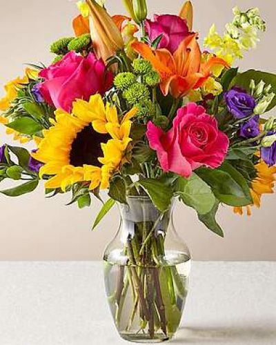 The Best Day™ Bouquet is ready to create a moment your recipient will always remember! An instant mood booster with it's mix of bright bold colors, this gorgeous fresh flower arrangement brings together sunflowers, hot pink roses, purple double lisianthus, orange LA Hybrid Lilies, yellow snapdragons, green button poms, and lush greens to make this day, their best day. Presented in a clear glass vase, this fresh flower arrangement is made just for you to help you send your warmest birthday, congratulations, or get well wishes to your favorite friends and family.
<ul>
<li>Our florists hand-design each arrangement, so colors, varieties and containers may vary due to local availability</li>
</ul>