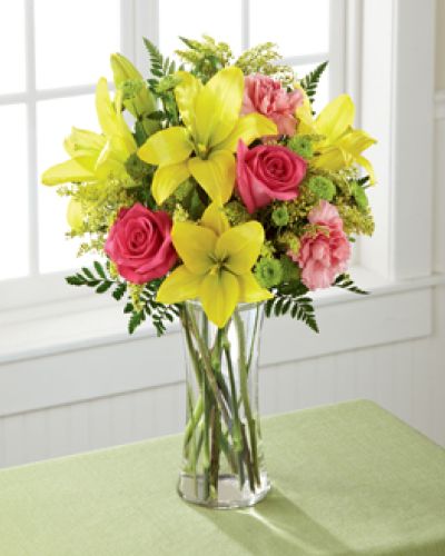 Light, lovely, and set to surprise and delight your recipient with it's bright blooms, this flower bouquet speaks to the magic that each day holds. Brilliant yellow Asiatic Lilies are surrounded by hot pink roses, pink carnations, yellow solidago, and lush greens, beautifully arranged in a classic clear glass vase to create a gift that exudes warmth and happiness. A wonderful way to celebrate a birthday, or express your thank you, or congratulations wishes!
<ul>
<li>Our florists hand-design each arrangement, so colors, varieties and containers may vary due to local availability</li>
</ul>